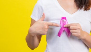 breast-cancer-a-woman-in-a-white-t-shirt-with-a-satin-pink-ribbon-on-her-chest-a-symbol-for-breast-cancer-awareness